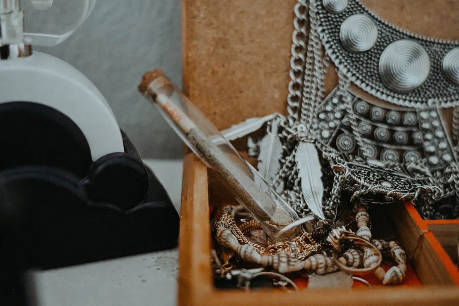 Smyckeslåda fylld med guldkedjor, silverhalsband och en glasflaska.