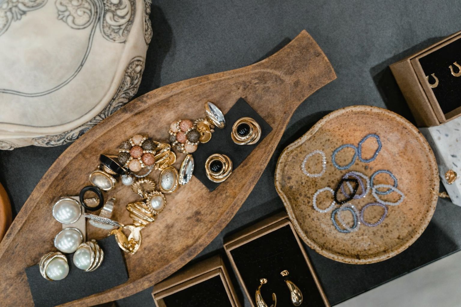 Olika vintageörhängen och pärlringar presenterade i träskålar och askar, redo för försäljning.